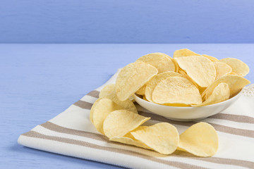 crispy potato chips on cotton fabric with light blue wooden background