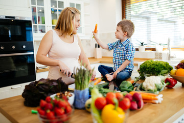 Pregnant woman preparing meal with son