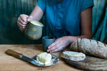 Foto op Canvas Woman has breakfast adds milk to coffee © greentellect
