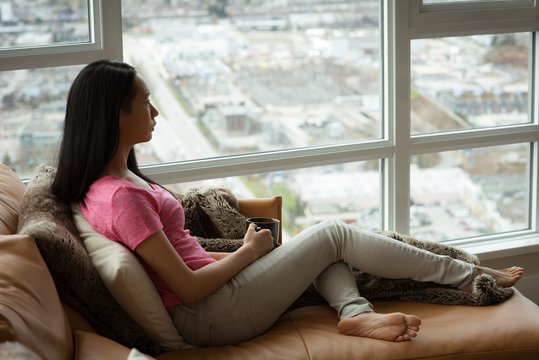 Woman Sitting On The Couch While Holding Coffee Mug