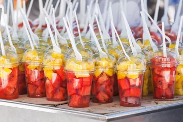 Wandaufkleber Sliced fresh fruits sorted in plastic cups with forks © evannovostro