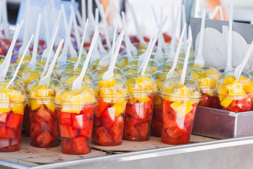 Fresh fruits sorted in plastic cups with forks