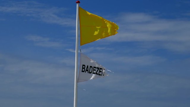 Wetter Fahnen am Strand vor blauen Himmel und weissen Wolken