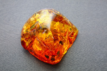 Natural amber. An unusually beautiful piece of transparent amber with inclusions and patterns on a gray background with a bokeh effect. Mineral for jewelry and advertising. Colored texture  of amber