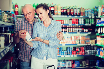 Adults woman and man choosing mayonnaise at the modern supermarket