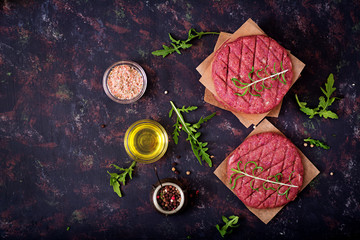 Fresh raw homemade minced beef steak burger with spices on black background