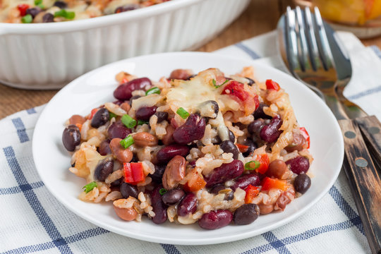 Baked rice casserole with black beans, pinto beans, kidney beans and cheese, on plate, horizontal