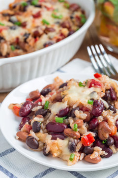 Baked rice casserole with black beans, pinto beans, kidney beans and cheese, on plate, vertical