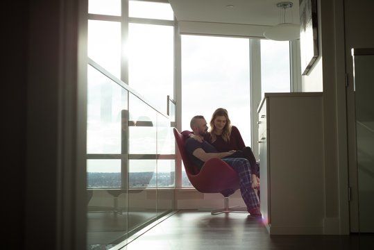 Romantic couple sitting together on a chair in living room