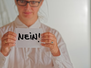 Frau mit wei&szlig;er Bluse h&auml;lt wei&szlig;e Karte mit dem Wort NEIN!