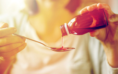 woman pouring medication from bottle to spoon