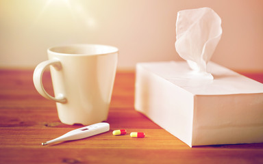cup of tea, paper wipes and thermometer with pills