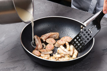 The cook pours the sauce into a frying pan with fried meat