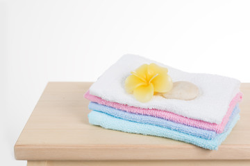 Obraz na płótnie Canvas Spa and treatment settting with zen stone, towels and frangipani flowers on wooden table isolated over white background