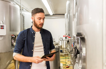man with tablet pc at craft brewery or beer plant