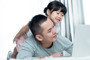 Young happy Asian father and daughter looking at the computer