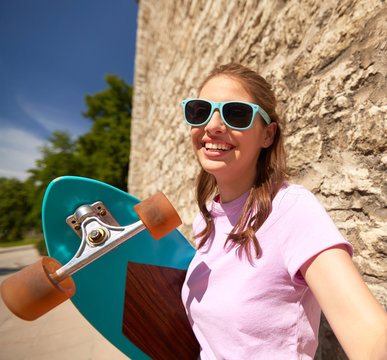 teenage girl with longboard taking selfie outdoors