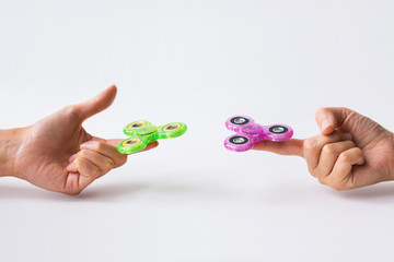 close up of two hands playing with fidget spinners