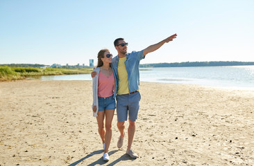 happy couple walking along summer beach