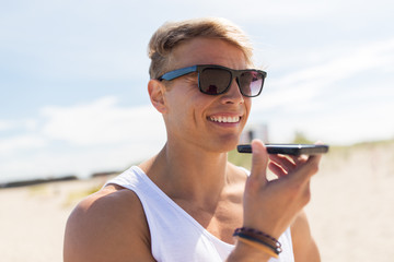 smiling man calling on smartphone at summer beach