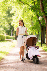 happy mother with smartphone and stroller at park