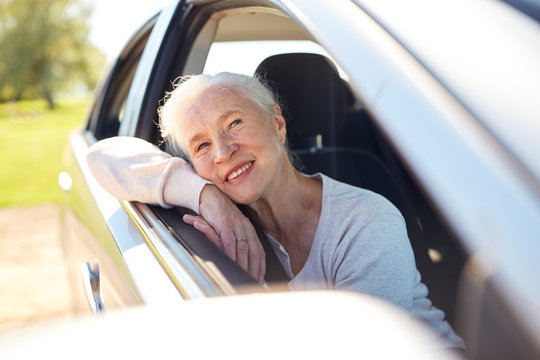 happy senior woman driving in car with open window