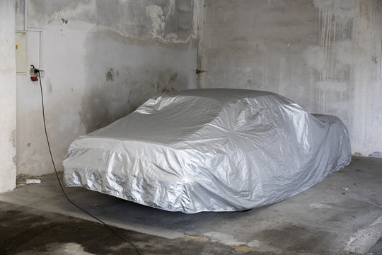 Car Covered Under Silver Sheet At Garage