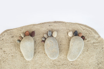 Group of pebble stones on sand creating de form of a foot in isolated white background
