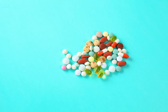Colored pills, tablets and capsules on a blue background