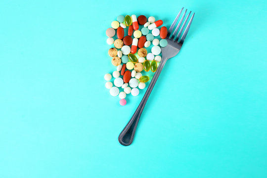 Many vitamins, sweets and pills on the table with a fork. Medications for lunch