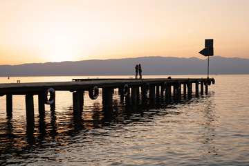 Obraz premium Silhouette of boat dock and girls on sunset.