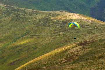A paraglider fly over a mountain valley on a sunny summer day. Paragliding in the Carpathians in...