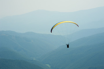 A paraglider fly over a mountain valley on a sunny summer day. Paragliding in the Carpathians in the summer.