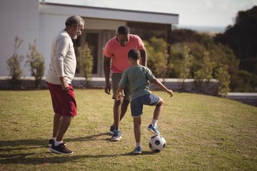 Obraz premium Boy playing football with his father and grandson