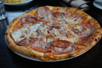 a huge pizza with different ingredients on a dark table