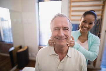 Portrait of smiling senior male patient and female therapist