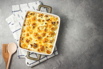 Cheesy cauliflower casserole on concrete background. Top view, space for text, toned.