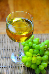 ein Glas weißwein mit Weintrauben auf einem Holztisch