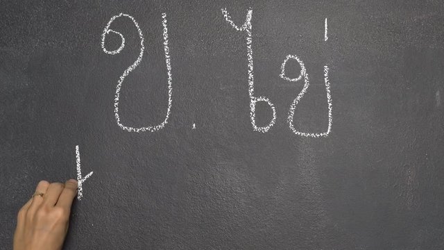 Woman's hand writing Thai letter "ข" with white chalk on blackboard