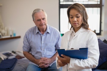 Senior male patient and female therapist looking at file