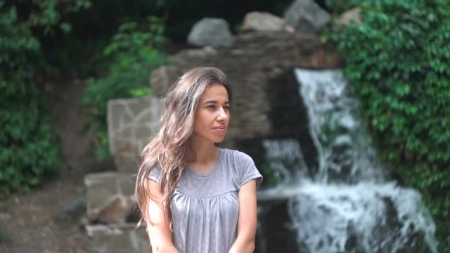 Beautiful young woman posing against a waterfall background.