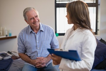 Smiling senior male patient looking at female therapist with