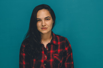 Fototapeta premium young brunette woman in a plaid shirt against a blue background