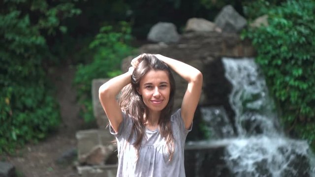 Beautiful young woman posing against a waterfall background.