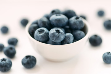 Blueberries in a white ceramic bowl on a white background, shallow depth of field