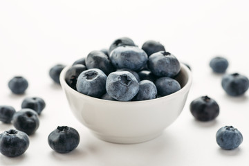 Blueberries in a white ceramic bowl on a white background, closeup shot