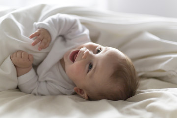 Cute happy 7 month baby girl in diaper lying and playing