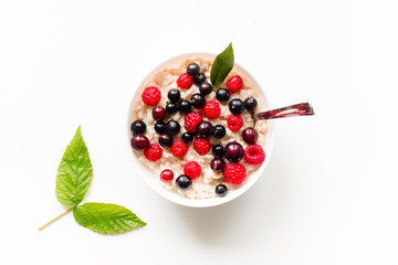 Oatmeal with forest berries and raspberry leaves on white background