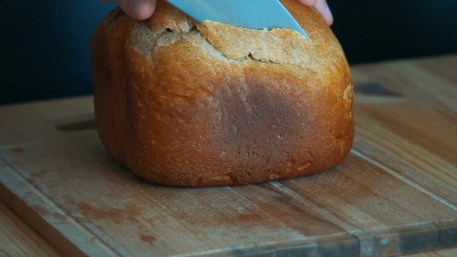 Man slicing tasty fresh whole grain bread. Healthy eating concept. Cutting artisan sourdough bread.