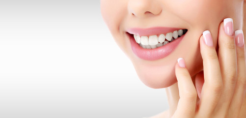 Closeup shot of woman's toothy smile against a grey background with copyspace